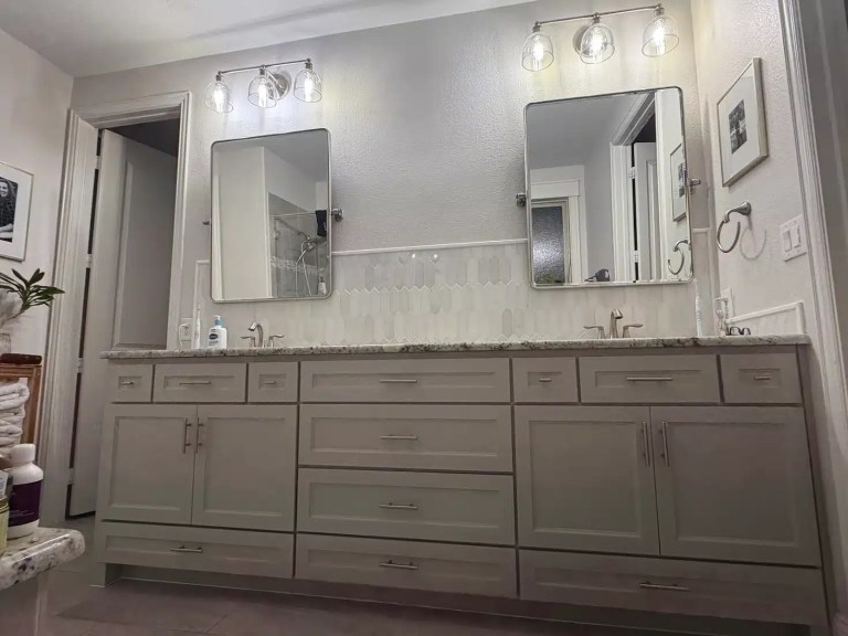 Custom double vanity The Colony TX featuring gray shaker cabinets, granite countertop, elongated hexagon picket tile backsplash, dual mirrors and brushed nickel hardware by I Love My Bathroom