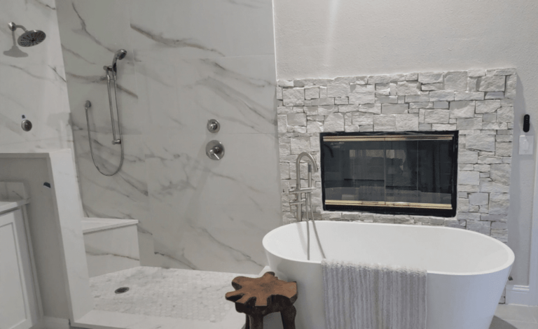 Master bathroom remodel Colleyville TX featuring marble porcelain tile freestanding soaking tub and stacked stone fireplace by I Love My Bathroom